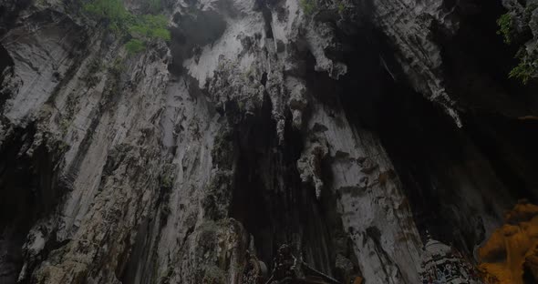 In Batu Caves seen cave with stalactite and walking tourists near the sacred temple