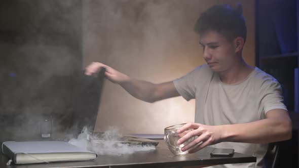 laptop starts to smoke while working. guy in panic pours coffee on the keyboard