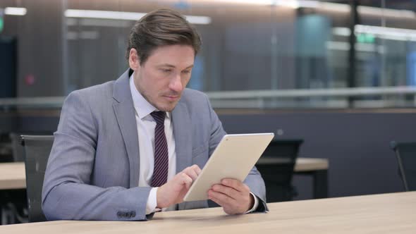 Middle Aged Businessman Working on Tablet 