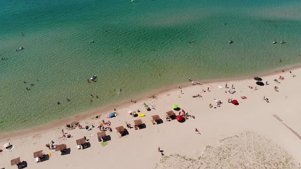 Aerial View of Azure Beach of Central Asia with Tourists Resting and Beach Umbrellas Top View