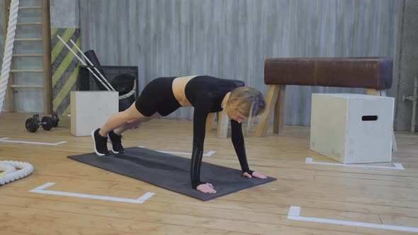 Beautiful female athlete doing exercise by running plank pose in gym. Fitness woman doing plank