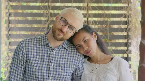 A Young International Interracial Couple in Love Looks Straight in To the Camera on a Sunny Day at