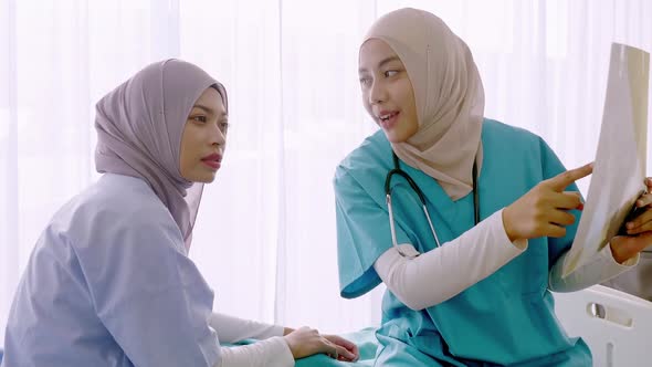 Expert doctor examining and explaining x-ray film to patient in hospital ward