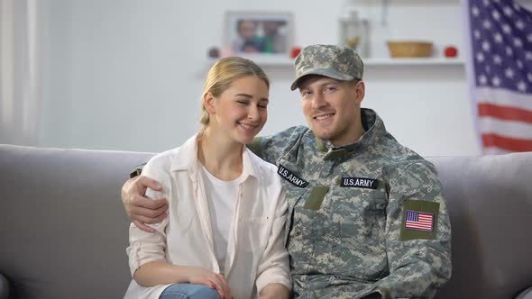 Happy US Army Soldier Hugging Wife Sitting on Sofa and Smiling at Camera Nation