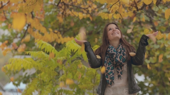 Cheerful Girl Standing Under Falling Leaves And