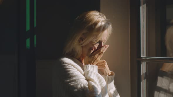 Sick Senior Woman Coughing Hard Standing Near Window at Home