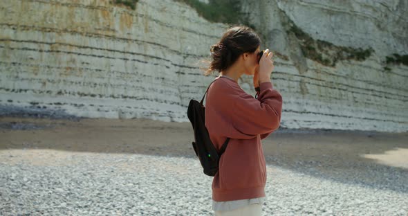 A Young Woman Walks Along a Pebbly Beach Past Sheer Chalk Cliffs