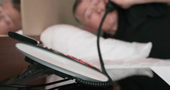 Man Sleeps on the Bed Next to the Phone