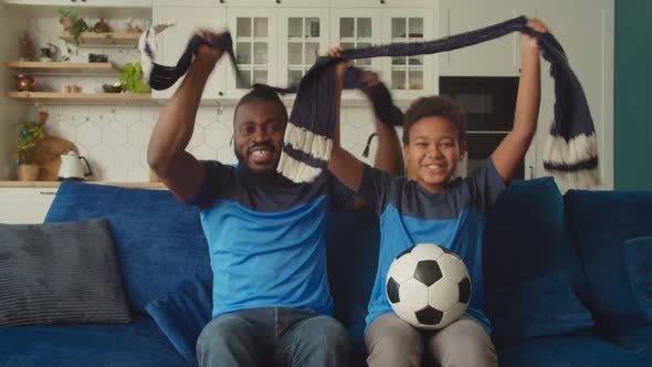 Excited African Family of Football Fans Watching Soccer on Tv and Cheering Team