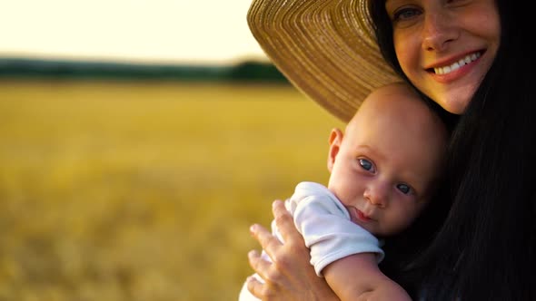 Portrait of loving mother kissing blue eyed baby in wheat field