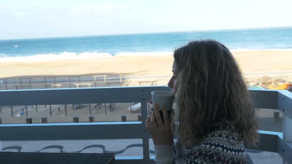 Girl Sits on Hotel Balcony with Notebook and Surfs Internet