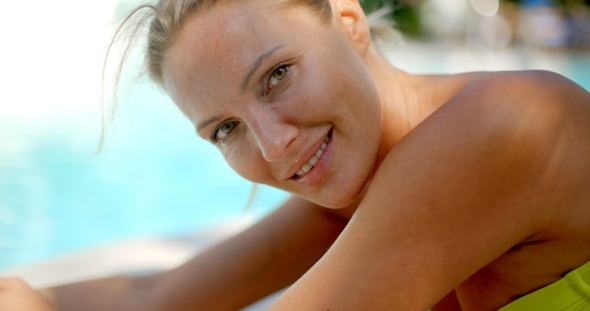 Blond Woman Smiling At Camera By Swimming Pool