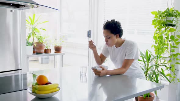 Happy woman using mobile phone while having breakfast 4k