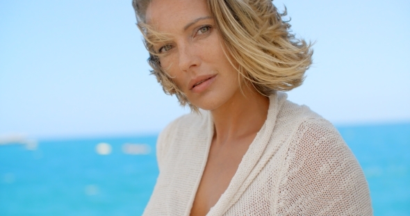 Blond Woman With Wind Swept Hair In Front Of Ocean