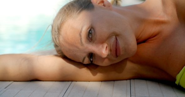 Blond Woman Lying On Side Next To Swimming Pool