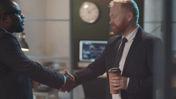 Multiethnic Businessmen Chatting over Coffee in Office