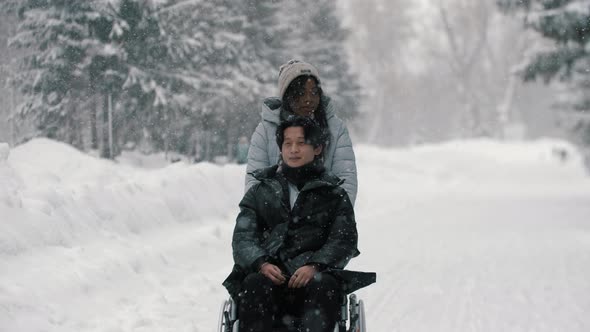 Asian Guy in the Wheelchair with His Black Girlfriend Walking in Winter Park