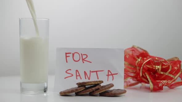 Closeup Cookies for Santa with Milk Pouring in Glass