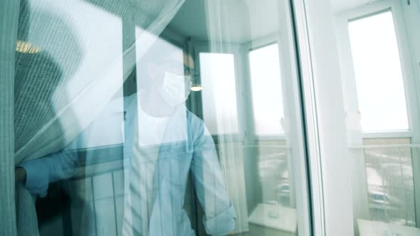 Adult Man in a Face Mask Is Looking Out of the Window