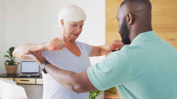 Video of happy african american male physiotherapist examining caucasian senior woman