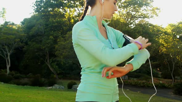 Woman adjusting music settings on armband from smartphone