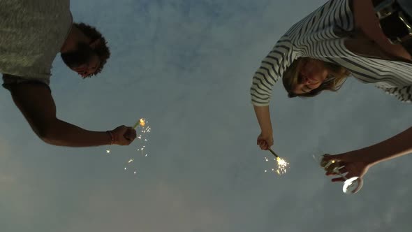 Under view of couple dancing with firework candles and holding champagne glasses