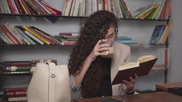 Young Moroccan Woman Drinking Coffee While Reading An Interesting Book alt