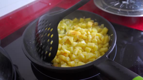 Stirring the onion and potatoes in a frying pan