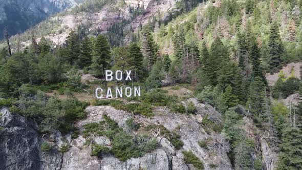 Aerial Pan Around Box Canyon Sign at Top of Mountain in Colorado