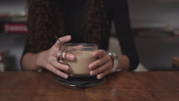 Girl Stirring Hot Coffee On Wooden Table And Then Smelled It