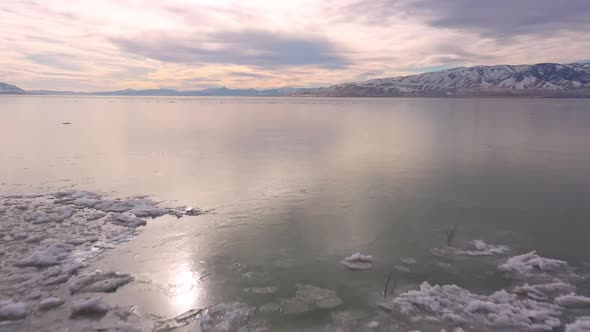 Flying backwards over smooth ice on lake past broken layers