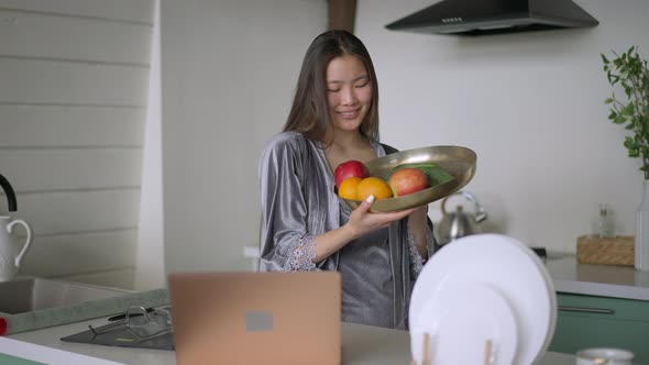 Portrait of Happy Young Slim Asian Woman with Toothy Smile Posing in Kitchen with Healthful Fruits