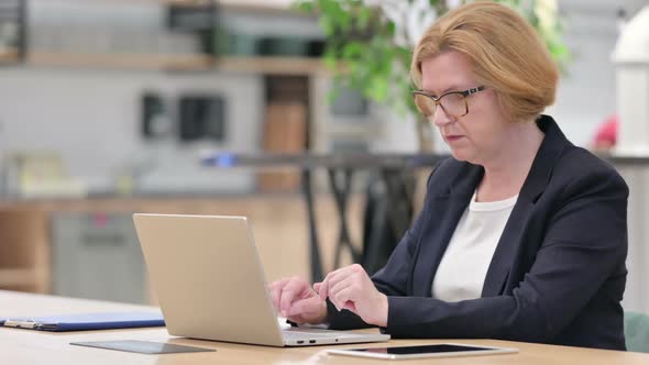 Old Businesswoman Having Loss on Laptop in Office