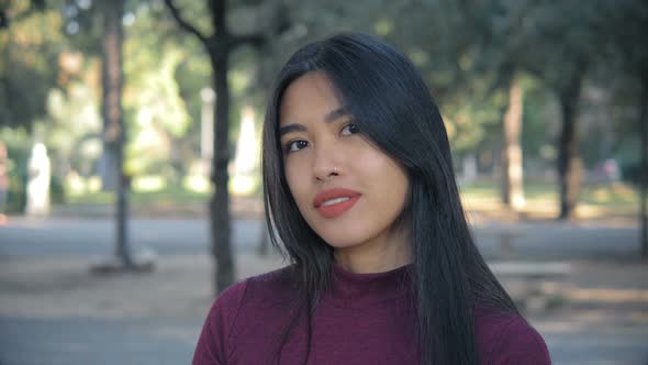 Asian sensual young woman turning and smiling at camera in the park