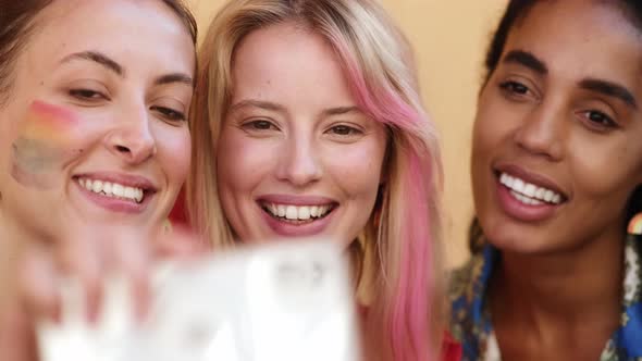 A close-up view of a group of smiling women are taking selfie photo using phone enjoying pride gay p