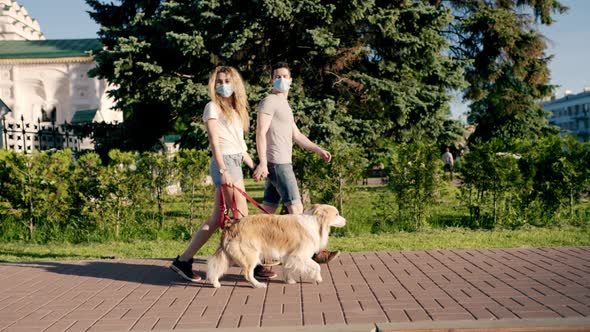 Loving Couple Man and Woman Wearing Mask Walking with a Border Collie Dog in City Park Relaxing