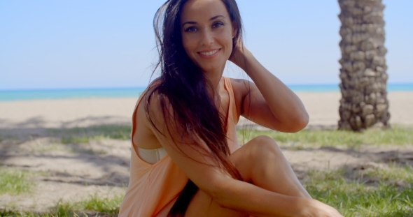 Attractive Woman Sitting At Grassy Beach Ground alt
