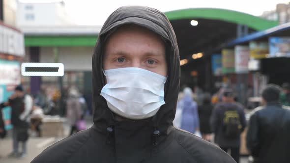 Portrait of Young Man with Medical Face Mask Stands at City Street. Guy Wearing Protective Mask From