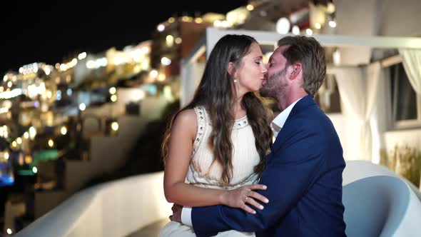 Romantic Couple Kissing Outdoors Evening on Private Porch in Fira Santorini