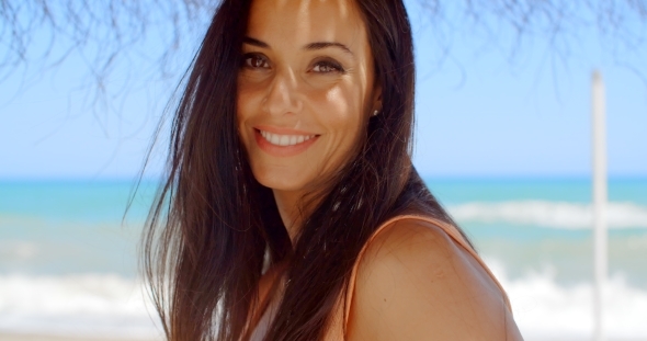 Woman Under a Beach Umbrella Smiling At Camera