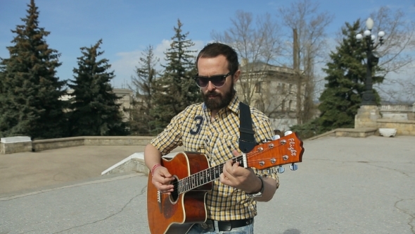 Sexy Guy With a Beard In Glasses Playing Guitar