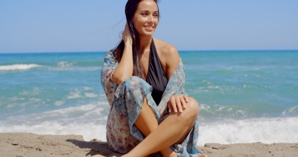 Smiling Attractive Woman Sitting On The Beach Sand
