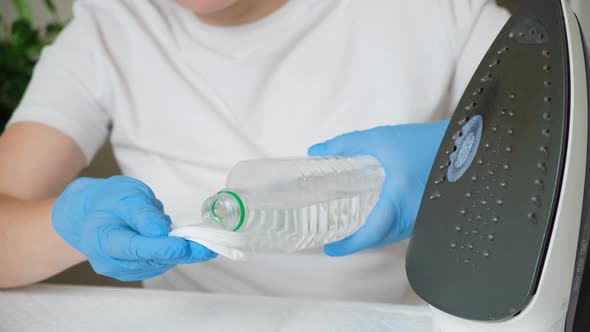 A Woman Cleans the Sole of an Iron with Vinegar