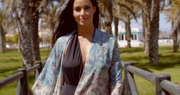 Woman Passing a Beach Pathway With Wooden Railings alt