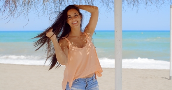 Happy Pretty Young Woman Under a Beach Umbrella