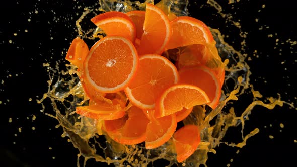 Super Slow Motion Shot of Rotating Exploded Orange Slices with Splashing Juice on Black at 1000Fps