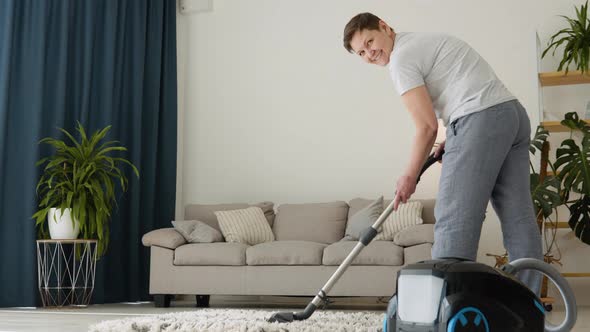 Senior Woman Vacuuming Carpet at Home