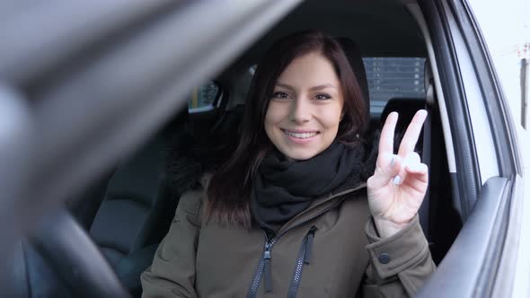 Victory Sign by Young Woman Sitting in Car