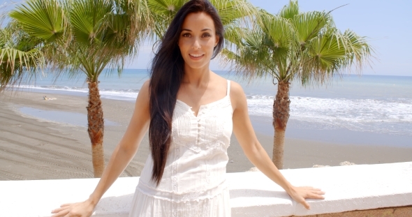 Woman In White Dress Leaning Against Beach Wall