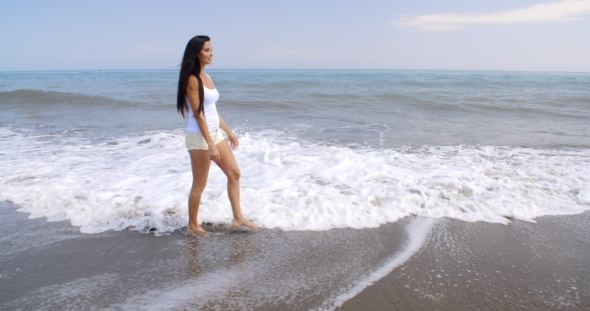 Woman Walking Along Shore Of Tropical Beach alt